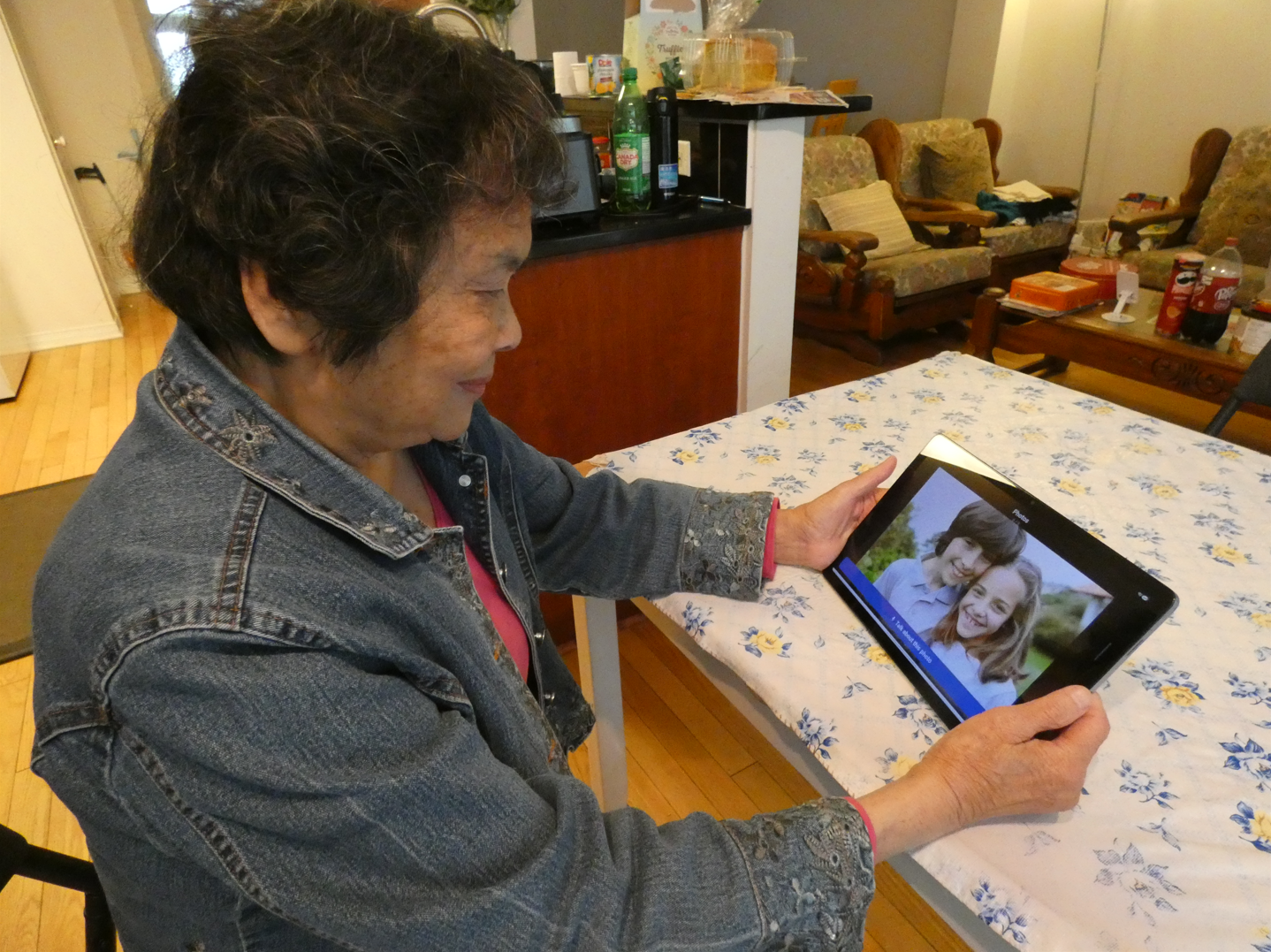 Xiaorong looking at a family photo on a tablet